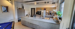 Una cucina moderna con isola centrale, elettrodomestici integrati e vista sull'area soggiorno.
