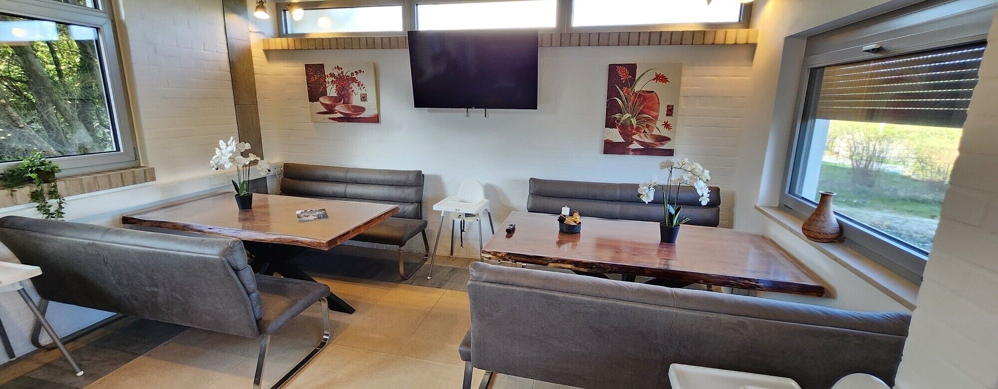 Un interior moderno con zona de comedor que incluye una mesa de madera y asientos tapizados en gris.