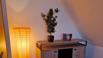 A wooden bench with a potted plant and books, a floor lamp, and a sloped ceiling.