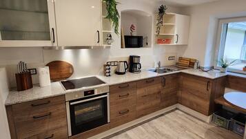 Una cucina moderna con mobili in legno, forno a incasso, microonde e macchina per il caffè.