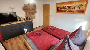 Une chambre moderne avec un lit, une télévision, un mur en briques et un tableau.