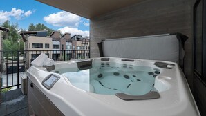 A hot tub on a balcony with a clear view of modern buildings in the background.