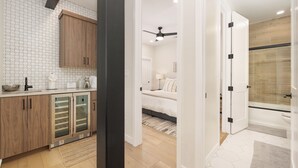 A modern kitchen with wooden cabinets and a built-in oven, a bedroom with a bed and ceiling fan, and a bathroom with a shower and toilet.