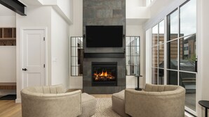 A modern living room with a fireplace, two sofas, and a large window.