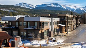 A modern hotel with multiple floors, large windows, and a view of snow-covered mountains.