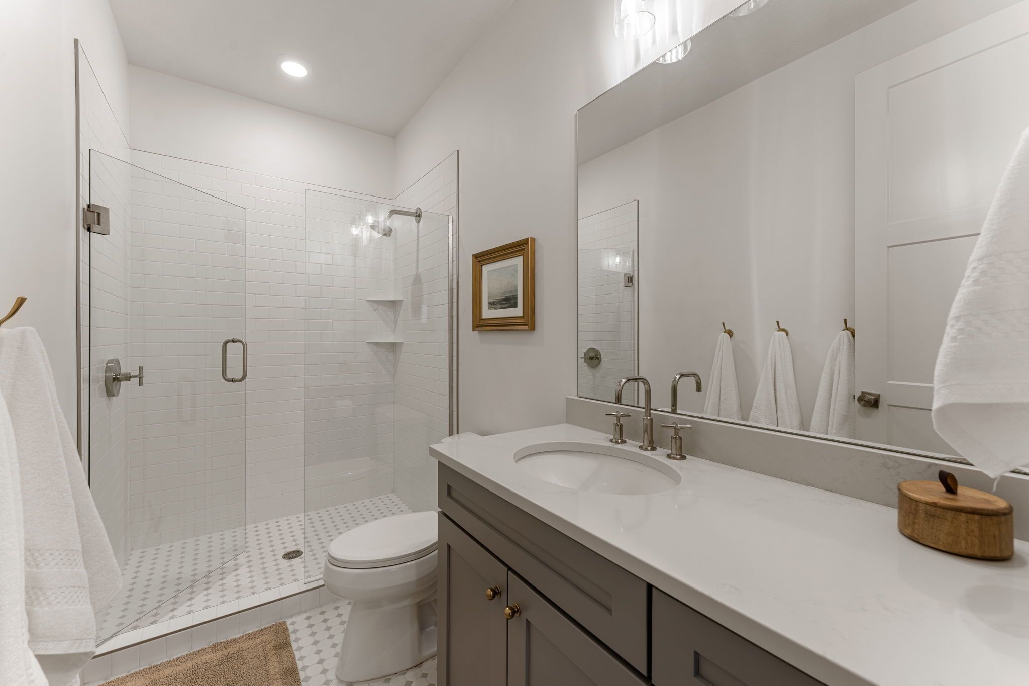 Une salle de bain moderne avec une douche à parois de verre, un grand miroir et un lavabo blanc.