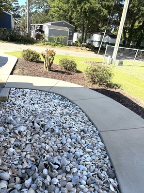 A landscaped area with a variety of seashells arranged along a curved concrete path. - Sandy Dreams, 2-bedroom dog-friendly duplex in Garden City w/fenced yard (Murrells Inlet)