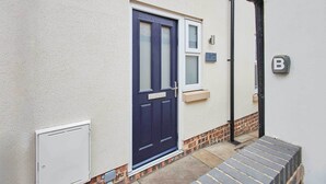 A front view of a house with a dark blue door, a small window above it, and a white mailbox. - Host & Stay | Bracken Cottage (Stokesley)
