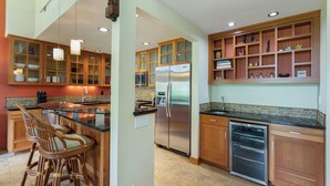 A spacious kitchen with wooden cabinets, a stainless steel refrigerator, and a built-in oven. - Princeville Island Charm Townhome - Puamana 19C (Princeville)
