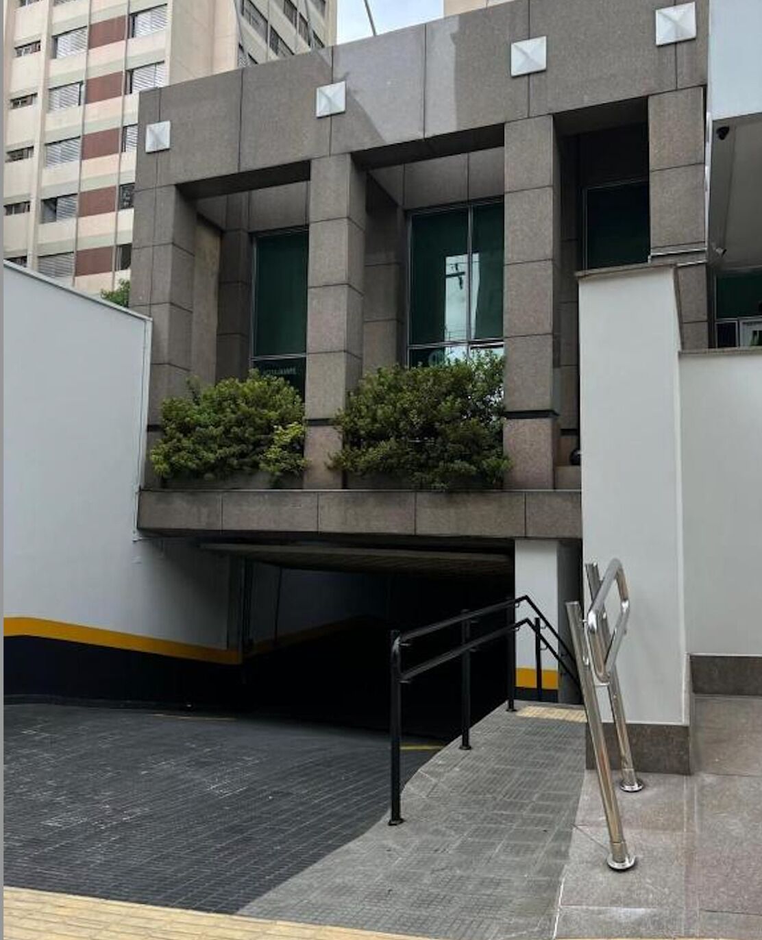 Un edifici modern amb teulada plana, grans finestres i una zona de pàrquing coberta amb barana metàl·lica.