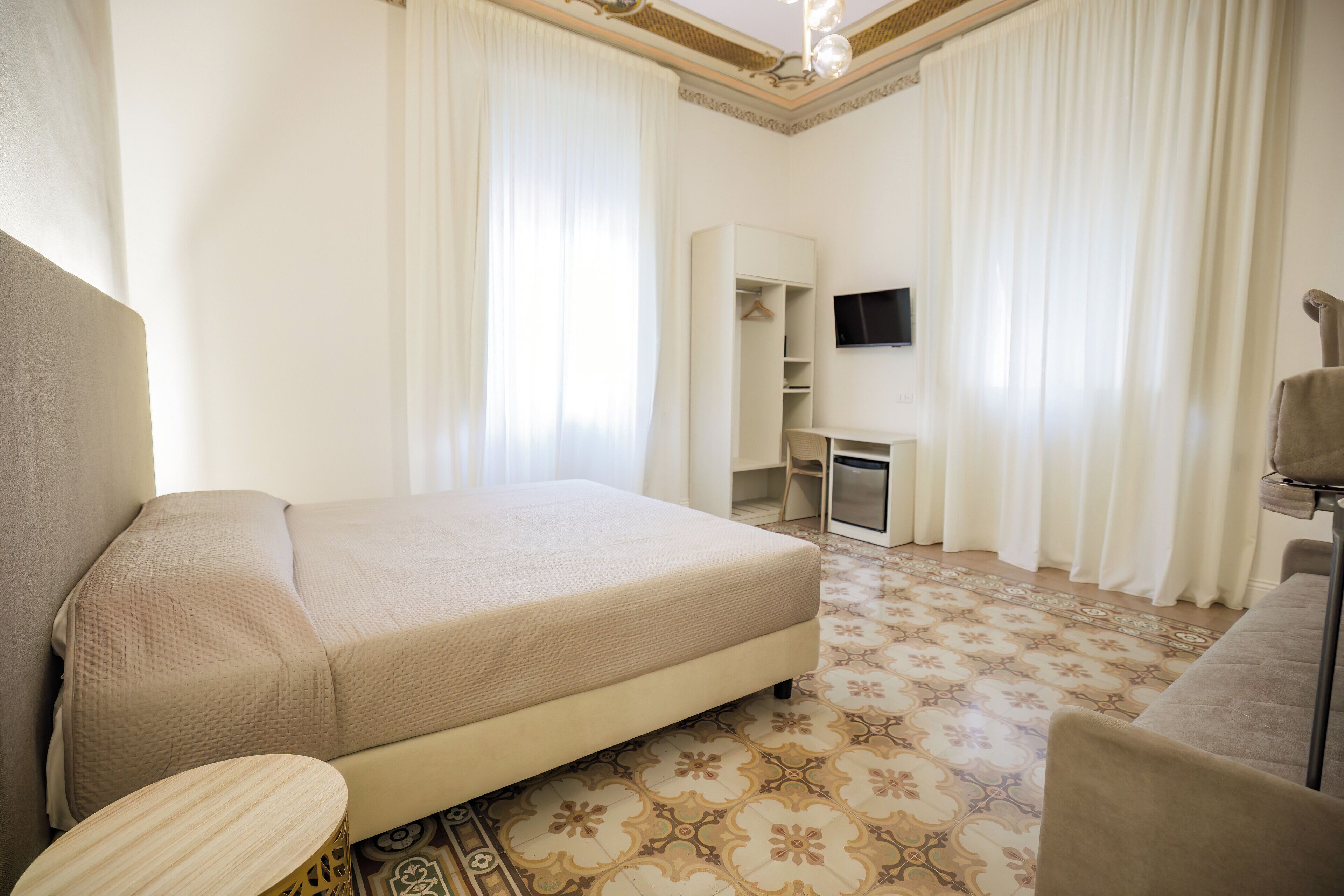 Una camera d'albergo con un letto, una scrivania, una TV e un armadio.