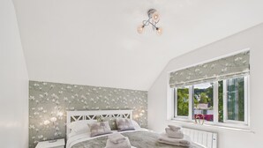 Une chambre à coucher comprenant un lit, une table de chevet, une fenêtre avec vue et un luminaire au plafond.