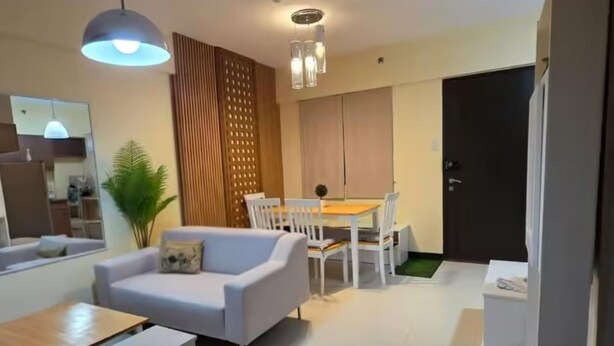Un salon moderne comprenant un canapé, une table à manger, des chaises et un coin cuisine.