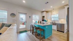 A modern kitchen with a central island, bar stools, and a dining area with a sofa. - Casa de Tortuga: 4  BR, 3  BA House in Crystal Beach, Sleeps 12 (Bolivar Peninsula)