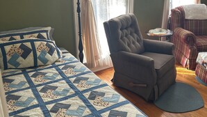 Une pièce confortable avec un grand lit, une chaise et une petite table.