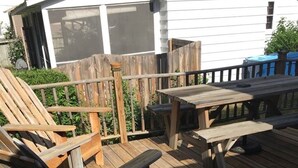 Une terrasse en bois avec une chaise en bois et une table de pique-nique.