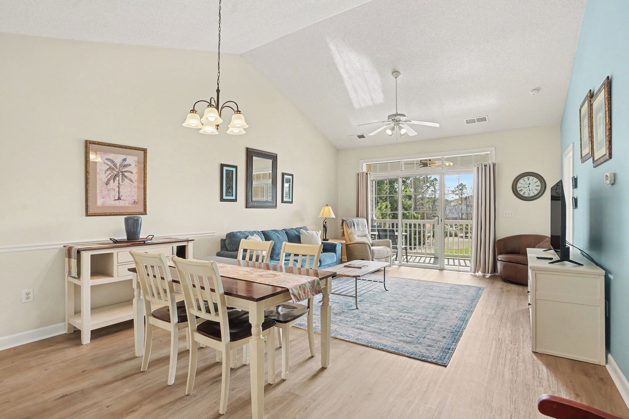 A spacious living area with a dining table, chairs, a sofa, and a TV on a cabinet.