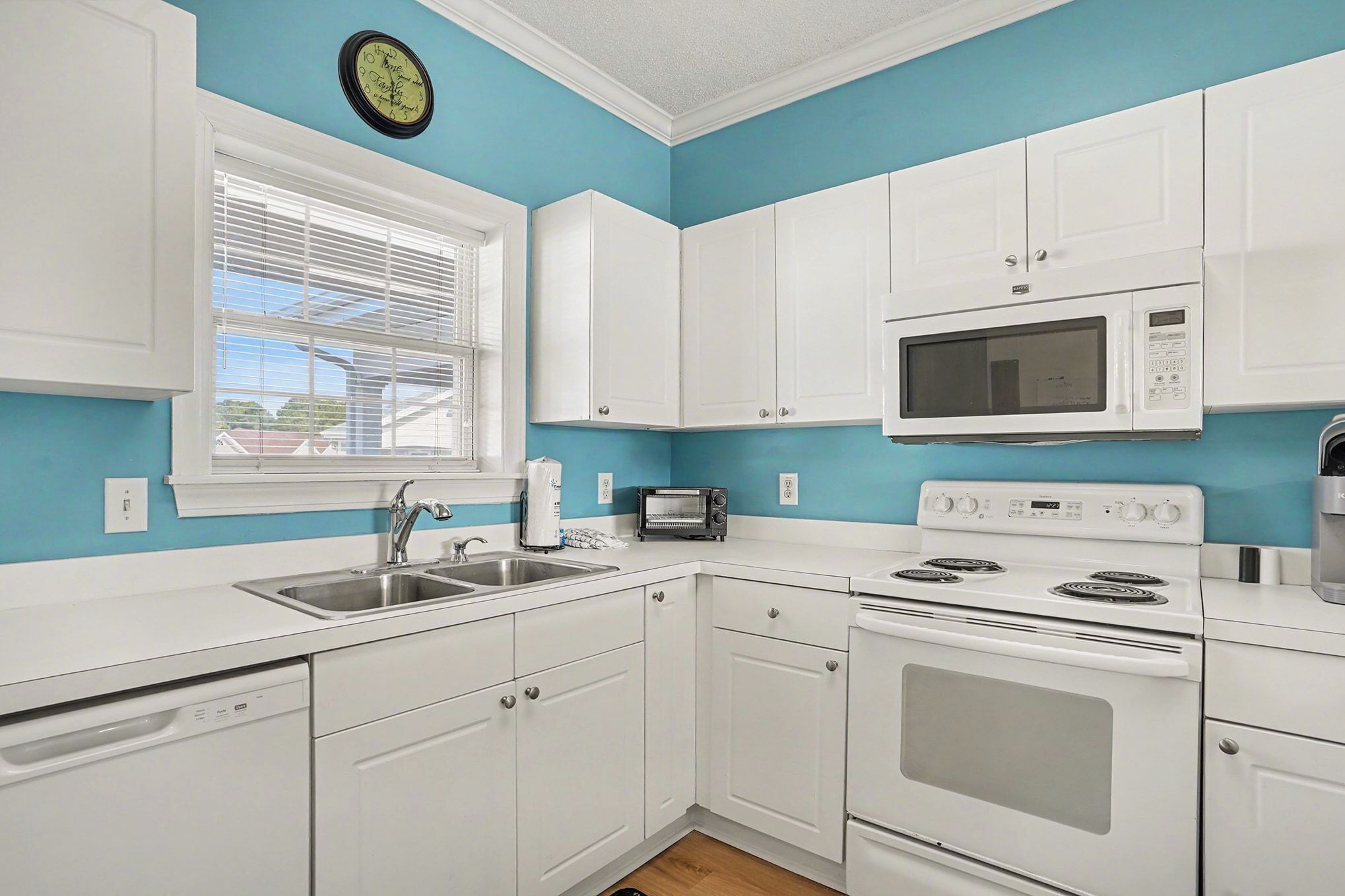 A kitchen with white cabinets, a microwave, a toaster, and a dishwasher.