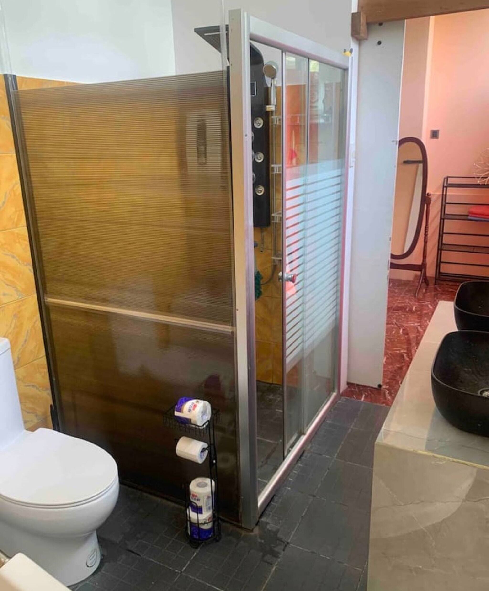 Un baño con cabina de ducha de vidrio, inodoro y lavamanos.