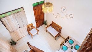 A spacious room with a wooden staircase, a dining area with turquoise plates, and a wooden door with a green panel. - Bucana Beach House North El Nido (El Nido)