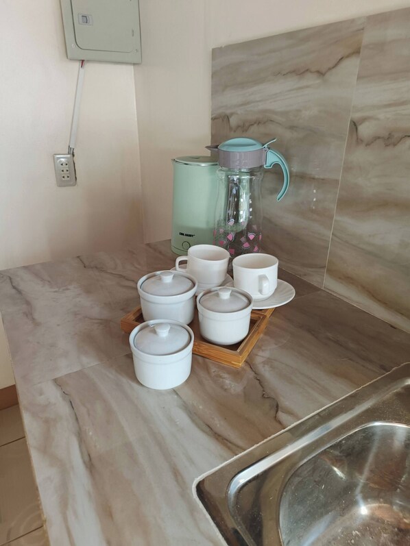 A kitchen counter with a coffee maker, a water dispenser, and a tray with six white cups. - Bucana Beach House North El Nido (El Nido)