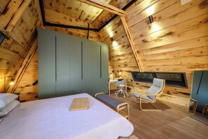 A cozy attic bedroom with a bed, a desk, and a chair, featuring wooden walls and a sloped ceiling. - A-Home Villa, Private Pool & Jetted Tub Oasis (Nea Alikarnassos)