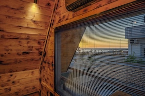 A room with wooden paneling and a large window with horizontal blinds.