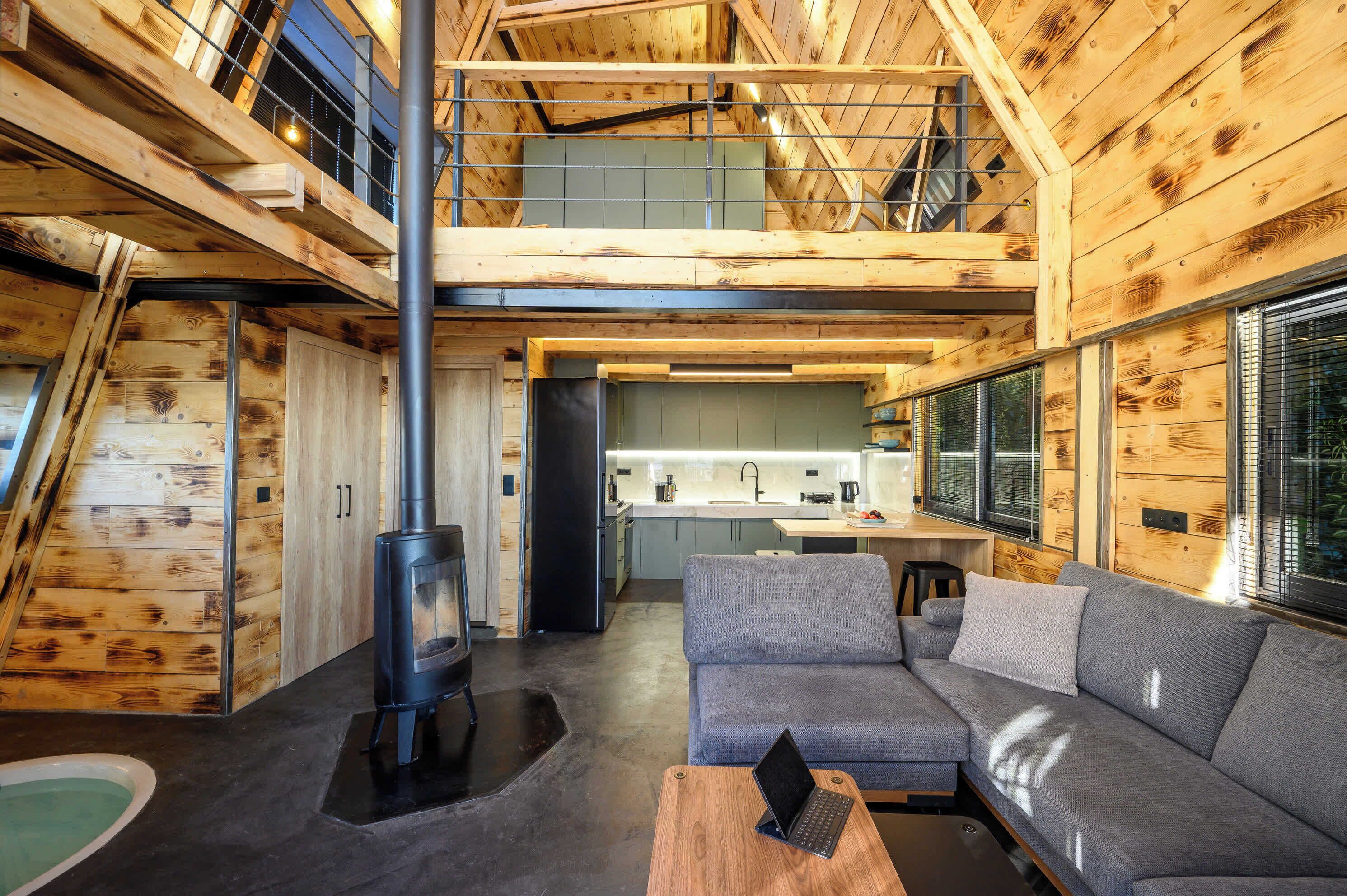L’intérieur d’une maison en rondins moderne, comprenant une cuisine, un espace de vie et une cheminée.