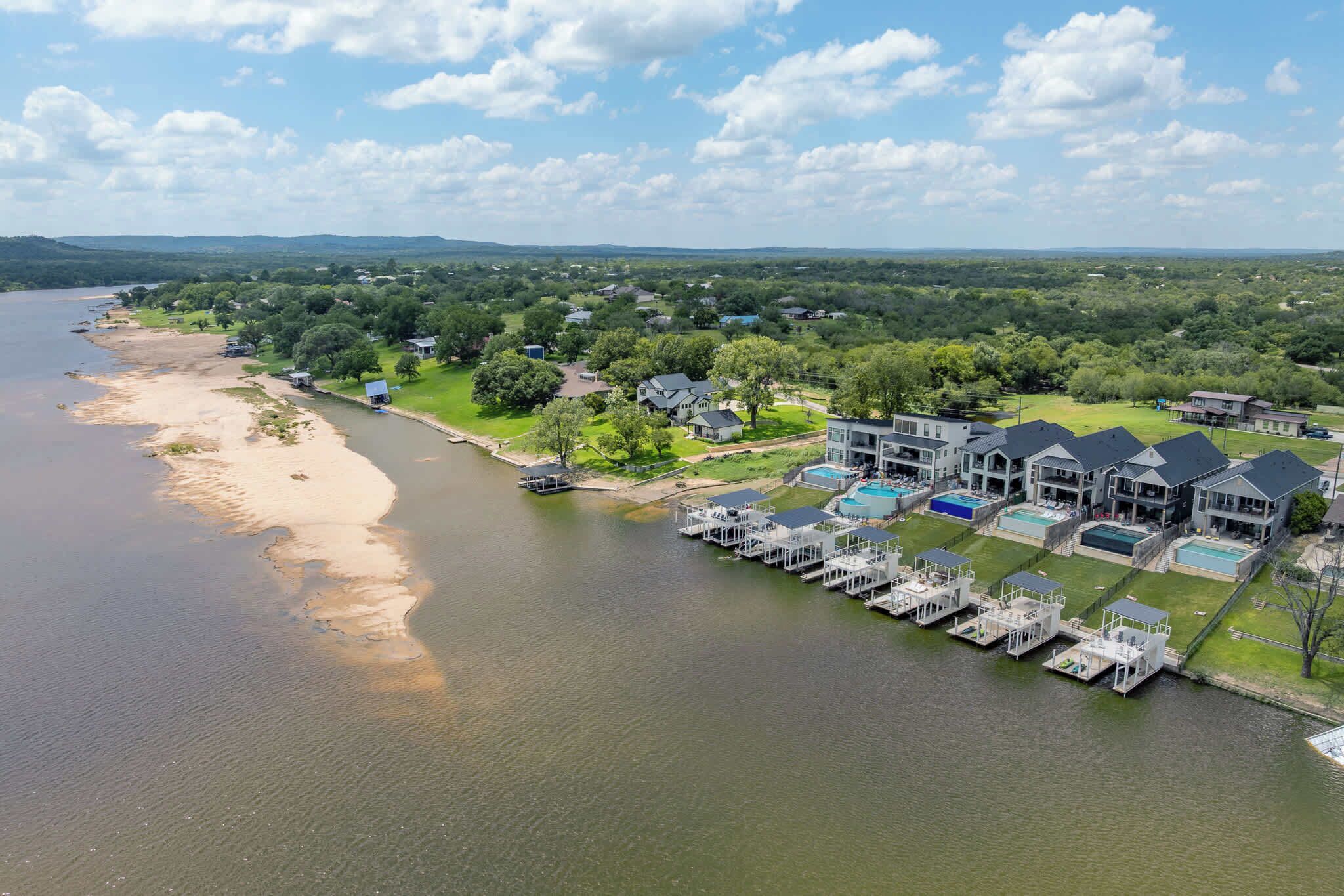 A lakeside residential area with houses, a dock, and a swimming pool.