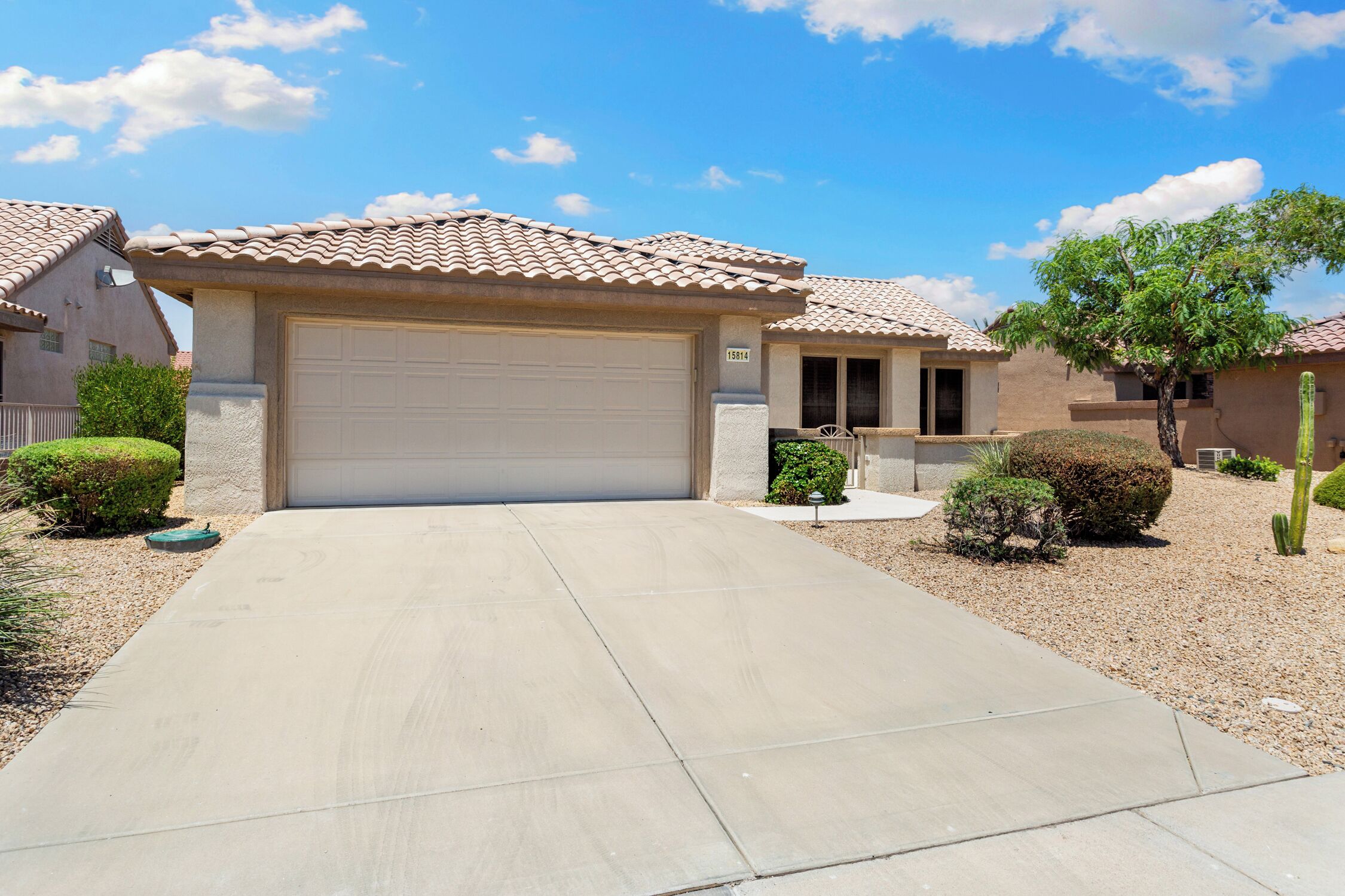 A residential area with houses featuring tiled roofs and a central driveway leading to a garage.