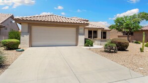 A residential area with houses featuring tiled roofs and a central driveway leading to a garage.