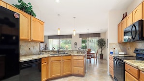A modern kitchen with wooden cabinets, granite countertops, and stainless steel appliances.