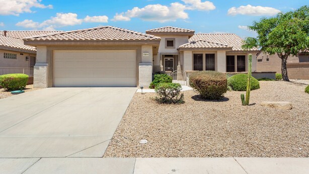 A residential house with a garage, a small porch, and a well-maintained garden with gravel and plants.
