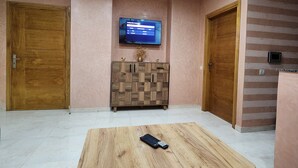 Eine Hotelhalle mit einem Holztisch, einem an der Wand befestigten Fernseher und zwei Holztüren.
