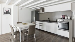 A modern kitchen with white cabinetry, a black countertop, and stainless steel appliances including a stove and oven. - Casa del Borgo by Wonderful Italy (Bologna)