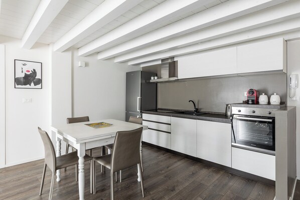 Une cuisine moderne avec des meubles blancs, un plan de travail noir et des appareils en acier inoxydable, notamment une cuisinière et un four.