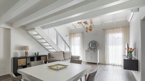 A spacious living area with a white table, a sofa, a staircase, and a dining area. - Casa del Borgo by Wonderful Italy (Bologna)