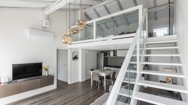 A modern loft-style apartment with a dining area, kitchen, and a loft space with a staircase. - Casa del Borgo by Wonderful Italy (Bologna)