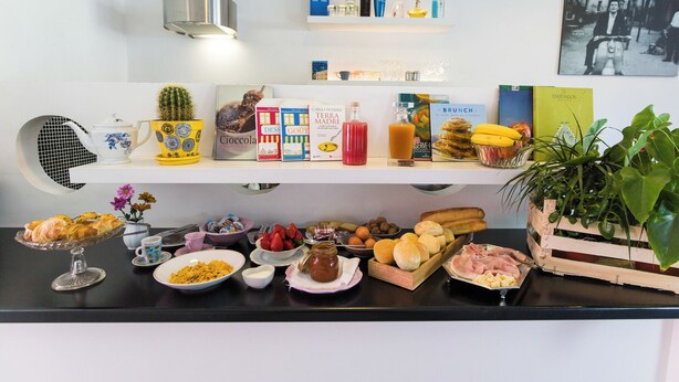 Un piano di lavoro della cucina con diversi cibi, libri e oggetti decorativi.