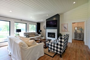 Una sala de estar moderna con chimenea, un sofá, una mesa de centro y una silla a cuadros.
