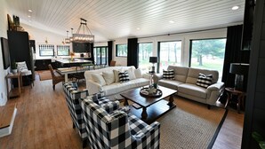 A spacious living area with a large sofa set, a coffee table, and a dining area with a chandelier.