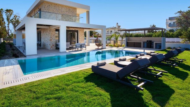 A modern house with a swimming pool, outdoor seating, and a stone facade. - Terra Magna - Alba Villa (Rhodes)