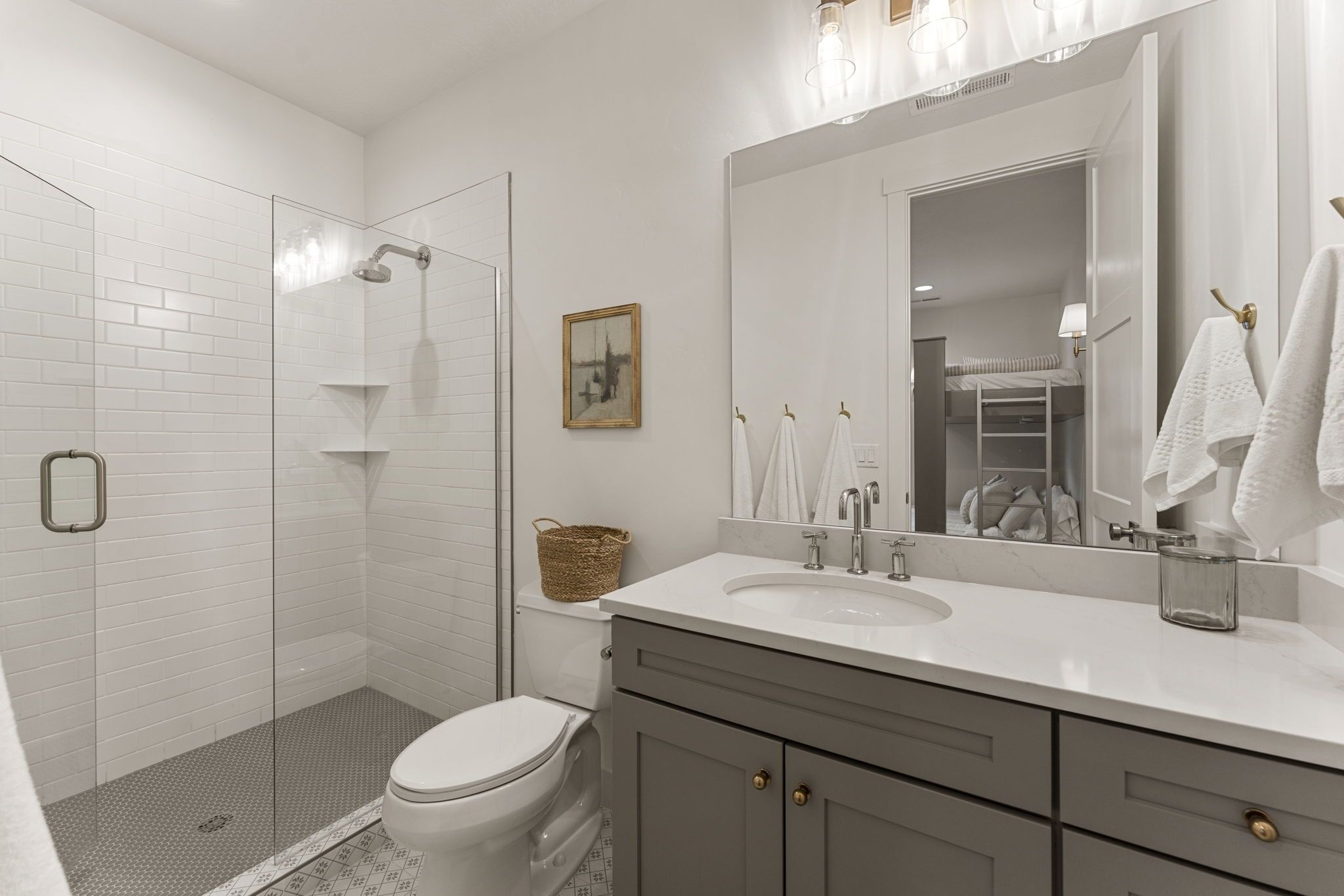 A modern bathroom with a glass shower enclosure, a toilet, a vanity with a sink, and a large mirror.