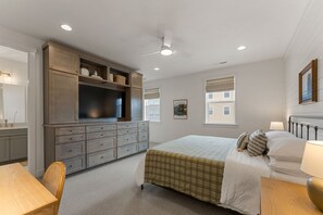Ein Schlafzimmer mit Bett, Schminktisch und Fernseher auf einem Schrank.