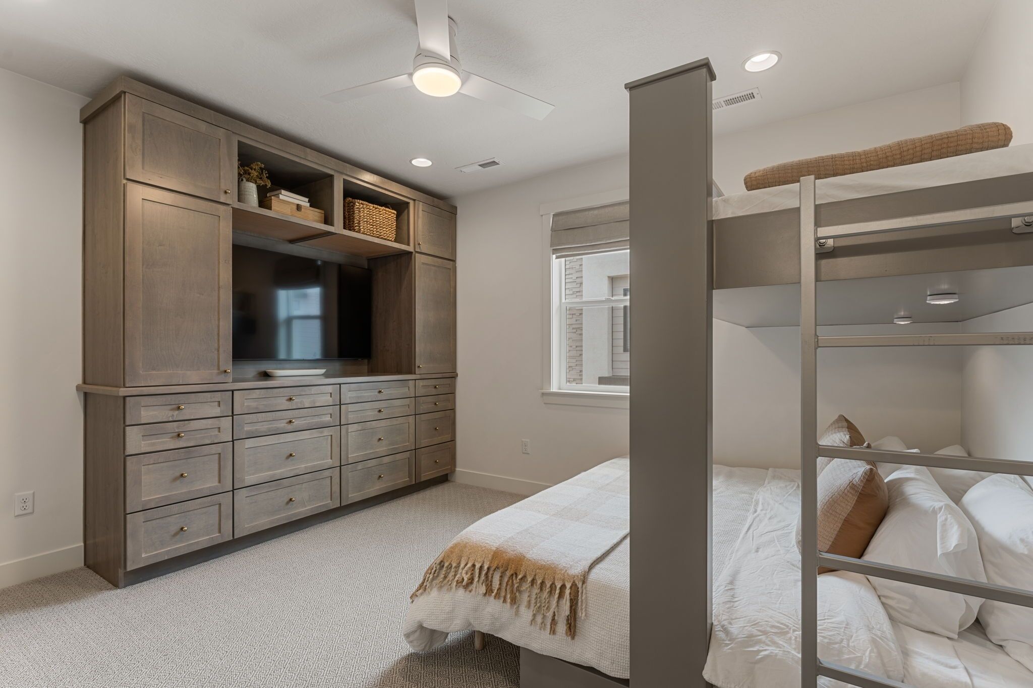 A bedroom with a bunk bed, a wardrobe, a television, and a window.