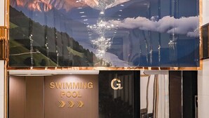 A hotel entrance with a large mountain mural, a chandelier, and a sign for the swimming pool. - Golden Empire Suvarnabhumi Hotel (Bang Phli)
