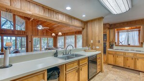 A kitchen with wooden cabinets, a large island with a sink, and a ceiling fan.