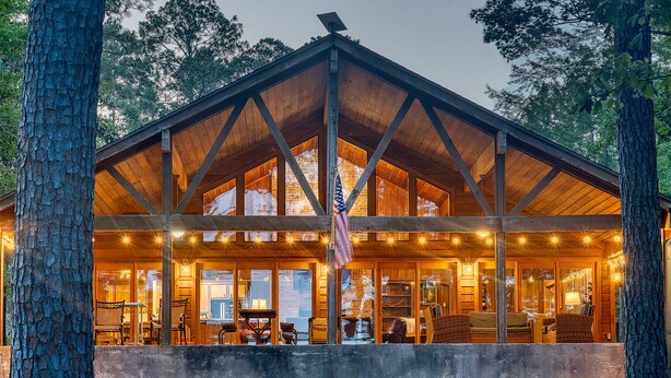 A lodge with a large open porch, wooden beams, and a flagpole.