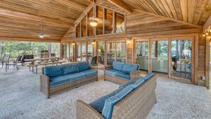 A spacious covered patio with wicker furniture, large windows, and a ceiling fan.