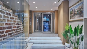 A modern lobby with a glass wall, a brick wall, and a staircase leading to a reception area. - Four - G Hotel Premium (İstanbul)